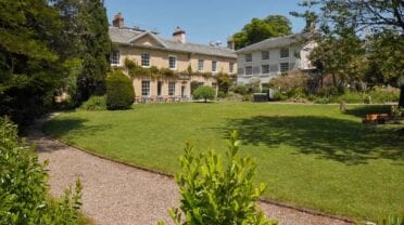 Tone Dale House, Somerset – Georgian country house with manicured lawn and mature trees surrounding gravel pathway.