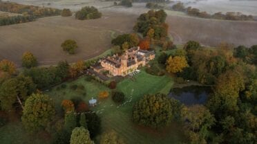 Thicket Priory, North Yorkshire – Aerial view of Victorian mansion with grounds, ornamental lake, and surrounding farmland in autumn.