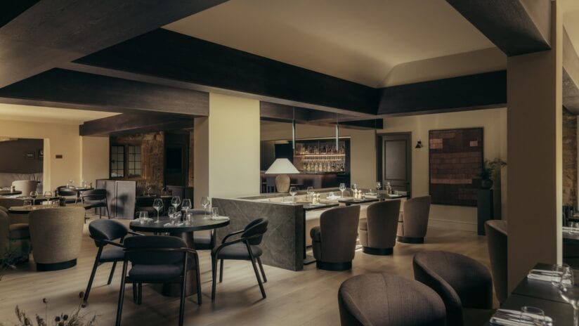 Hyll Hotel, Gloucestershire – Open-plan kitchen and dining area with dark timber beams and marble island counter.