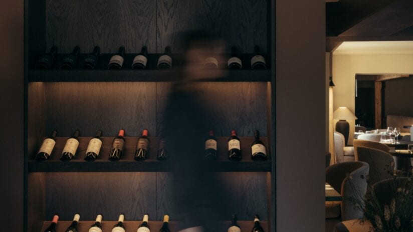 Hyll Hotel, Gloucestershire – Dark wood wine display cabinet with illuminated shelves holding wine bottles.