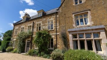 Belvoir Lodge, Lincolnshire – Stone country house with ivy-covered walls and multi-pane windows, gravel forecourt.