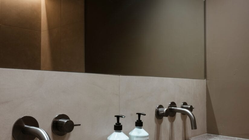Hyll Hotel, Gloucestershire – Modern bathroom vanity with black fixtures, white tile splashback, and illuminated mirror.