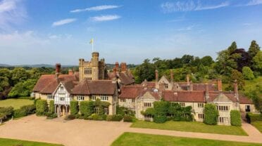 Cowdray House – Castellated country house with brick and stone façade, manicured lawns and gravel driveway