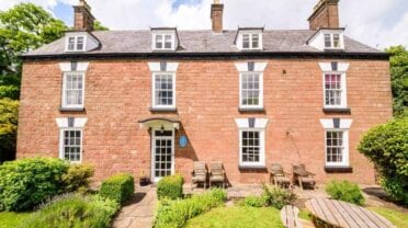 Forest House, Gloucestershire – Georgian red-brick country house with dormer windows, manicured garden and wooden loungers.