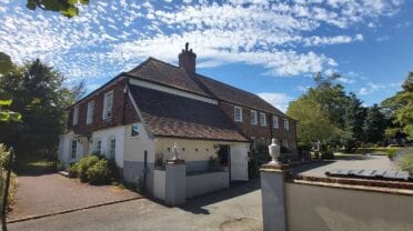 Great Everden Manor – Brick country house with cream and brown rendered exterior, central chimney stack, and manicured grounds