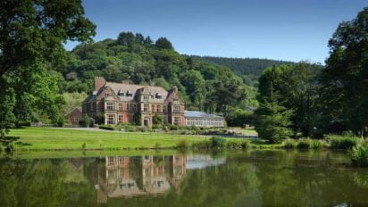 Knowle Manor – Victorian mansion with red brick façade and mansard roof beside tree-lined lake.