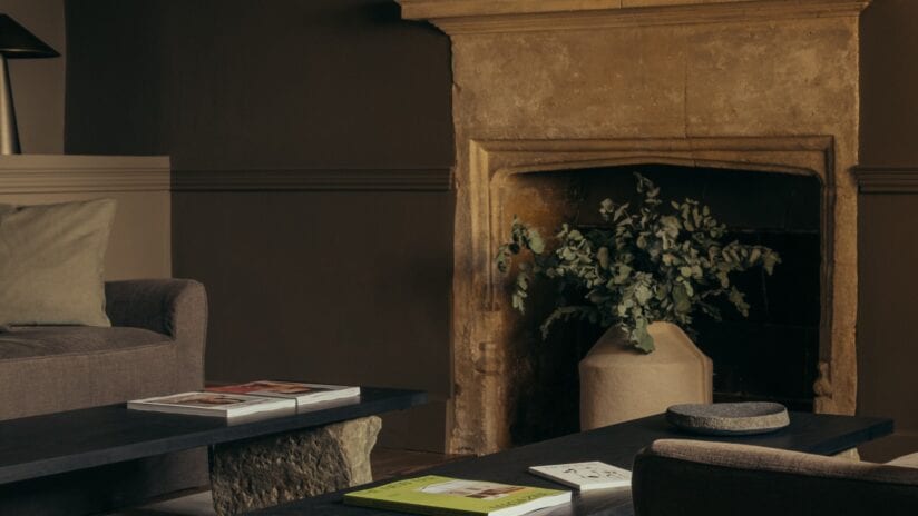 Hyll Hotel, Gloucestershire – Stone fireplace with dried foliage arrangement in contemporary living room with black table.