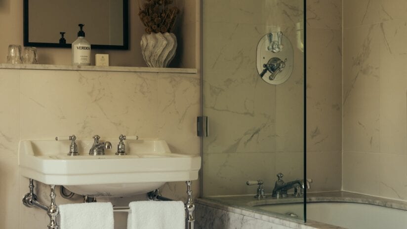 Hyll Hotel, Gloucestershire – Marble bathroom with pedestal sink and walk-in shower enclosure.
