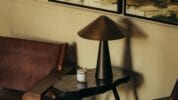 Hyll Hotel, Gloucestershire – Bedside table with brass cone lamp, marble top, and scented candle near leather headboard.