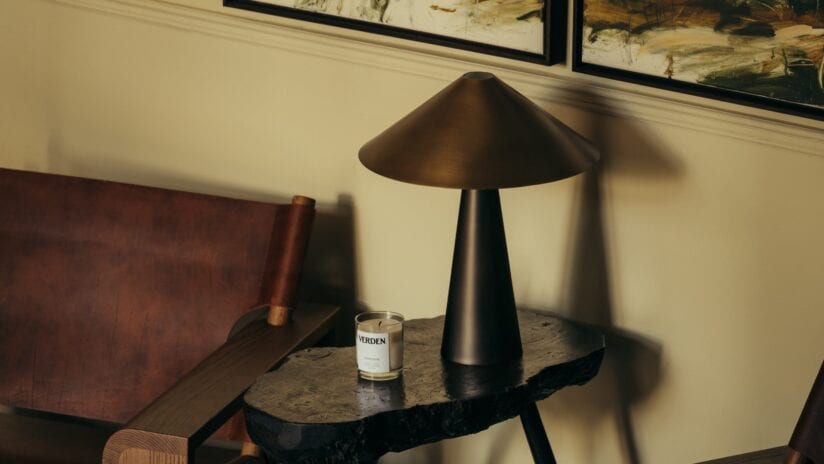 Hyll Hotel, Gloucestershire – Bedside table with brass cone lamp, marble top, and scented candle near leather headboard.