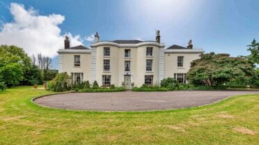 The Old Georgian Rectory, Gloucestershire – Cream-rendered Georgian mansion with curved driveway and manicured lawns.