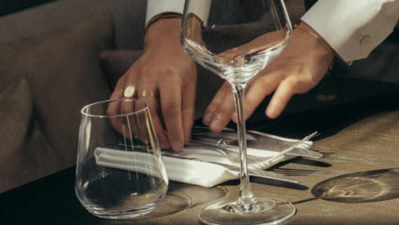 Hyll Hotel, Gloucestershire – Person pouring water into wine glasses at wooden dining table.