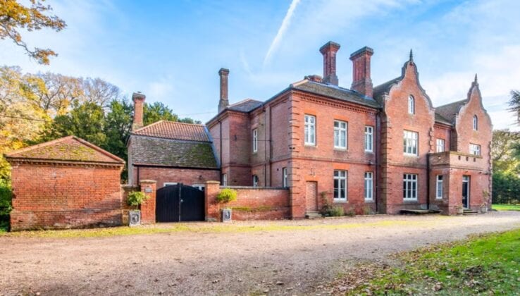 Bessingham Manor, Norfolk – Red brick Victorian manor house with multiple chimneys and pitched gable ends, gravel driveway and adjoining outbuilding.