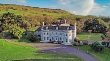 Smedmore House, Dorset – White-painted country house with curved facade, surrounded by parkland and rolling hills.